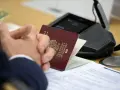 Dłonie złożone na stole, obok paszportu i dokumentów. Szykuje się wyrobienie paszportu w Bydgoszczy.