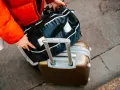 Osoba w czerwonej kurtce pakuje torbę podróżną na walizce. Zastanawiasz się, ile kosztuje bagaż rejestrowany?