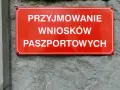 Czerwona tablica informuje o przyjmowaniu wniosków paszportowych. Czy żona może odebrać paszport męża? Sprawdź w urzędzie.