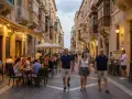 Ludzie spacerują i jedzą w restauracjach na ulicy w Valletcie. Czy podróż na Maltę jest bezpieczna? Tak, wygląda na to, że jest to bezpieczne i przyjemne miejsce.