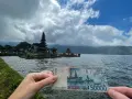 Ręka trzyma banknot 50 000 rupii na tle świątyni na wodzie. Czy Indonezja jest bezpieczna? Tak, podróżowanie po niej jest bezpieczne.