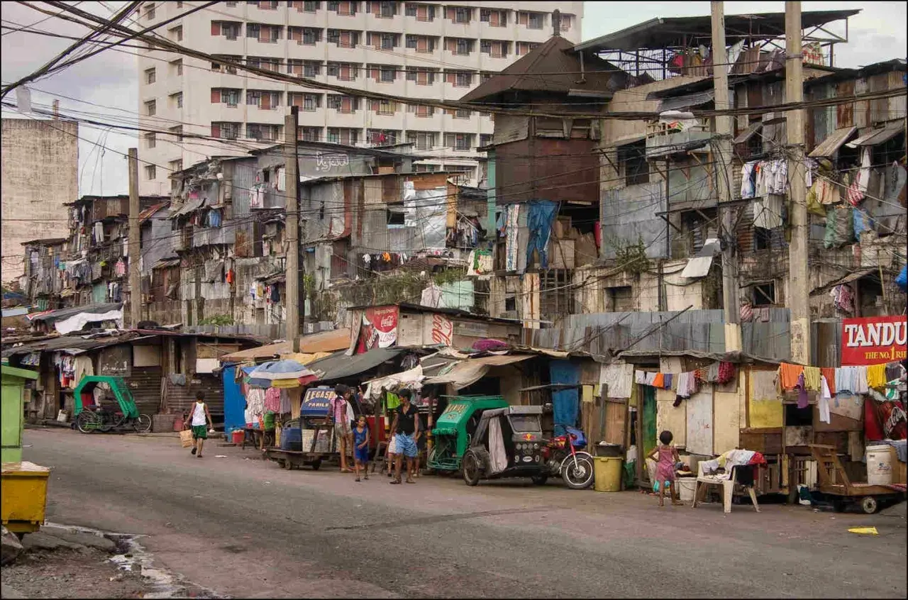 Uliczka w slumsach na Filipinach, gdzie życie toczy się wśród prowizorycznych domów i wszechobecnego prania. Czy w filipinach jest bezpiecznie? To pytanie nabiera nowego znaczenia w takich miejscach.