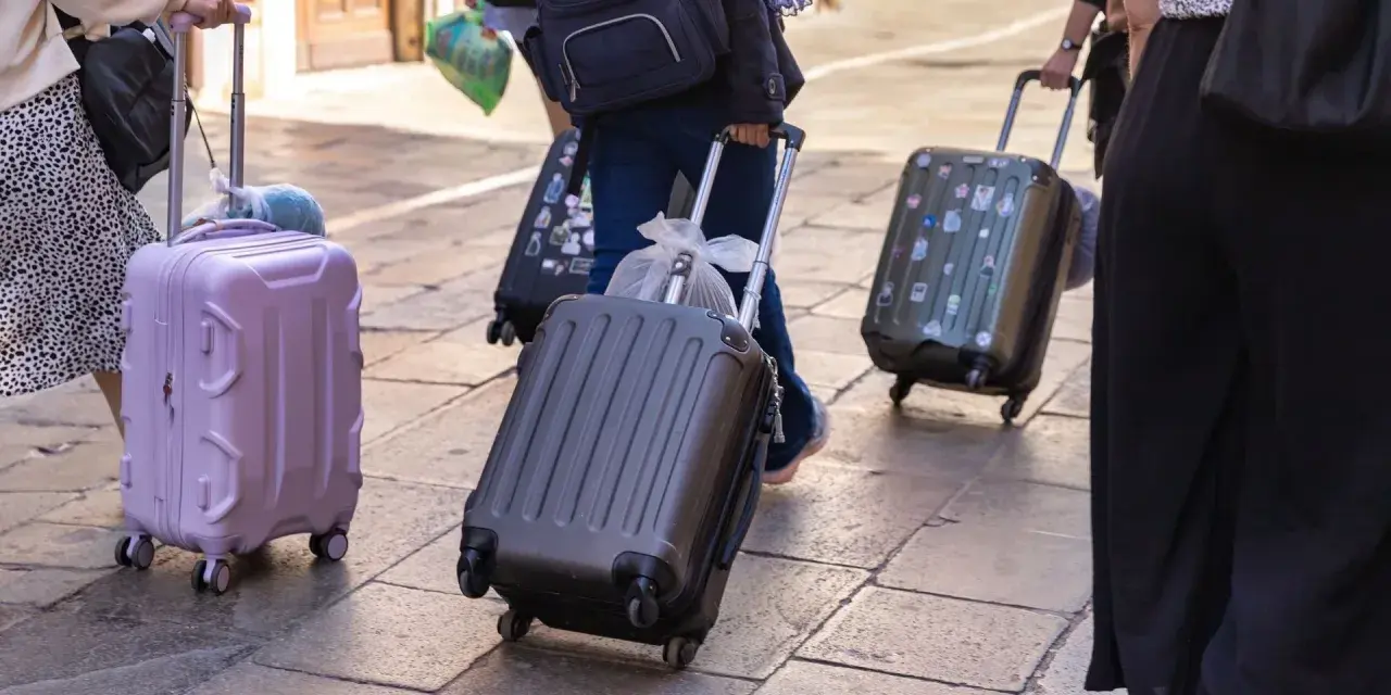 Ludzie z walizkami na kółkach, zastanawiający się, ile dopłata za bagaż Ryanair.