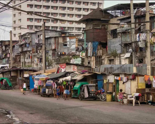 Uliczka w slumsach na Filipinach, gdzie życie toczy się wśród prowizorycznych domów i wszechobecnego prania. Czy w filipinach jest bezpiecznie? To pytanie nabiera nowego znaczenia w takich miejscach.