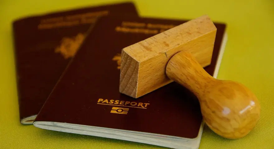 Drewniany stempel nad paszportem, gotowy do pieczętowania. Marzysz o podróży? Biuro paszportowe Lublin pomoże Ci spełnić marzenia.