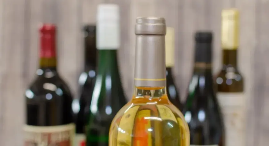 Butelki z winem na tle drewnianej ściany. Zastanawiasz się, ile alkoholu można wziąć do Norwegii samolotem?