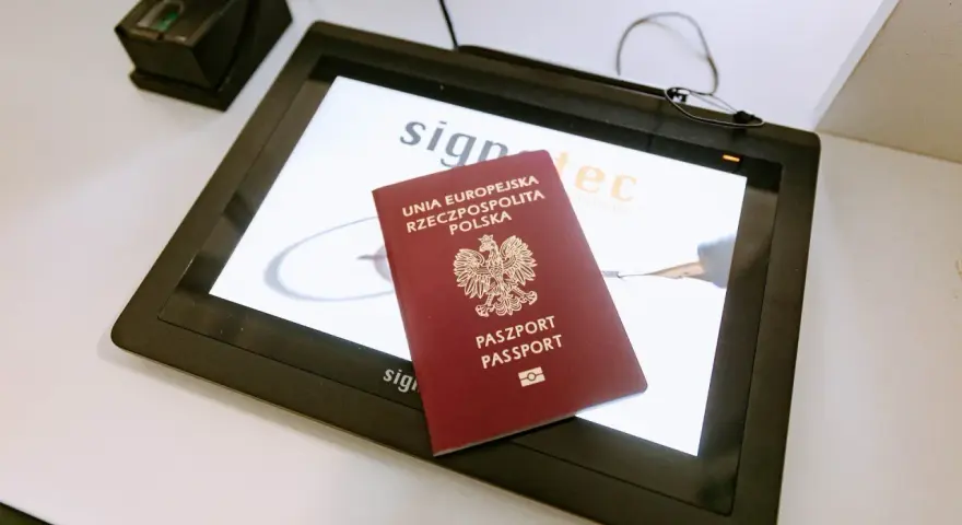 Polski paszport na ekranie tabletu w biurze paszportowym Włocławek. Obok skaner linii papilarnych.