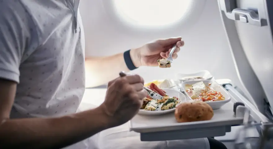 Pasażer je posiłek na pokładzie samolotu. Zastanawiasz się, czy można przewozić jedzenie w bagażu rejestrowanym Ryanair?