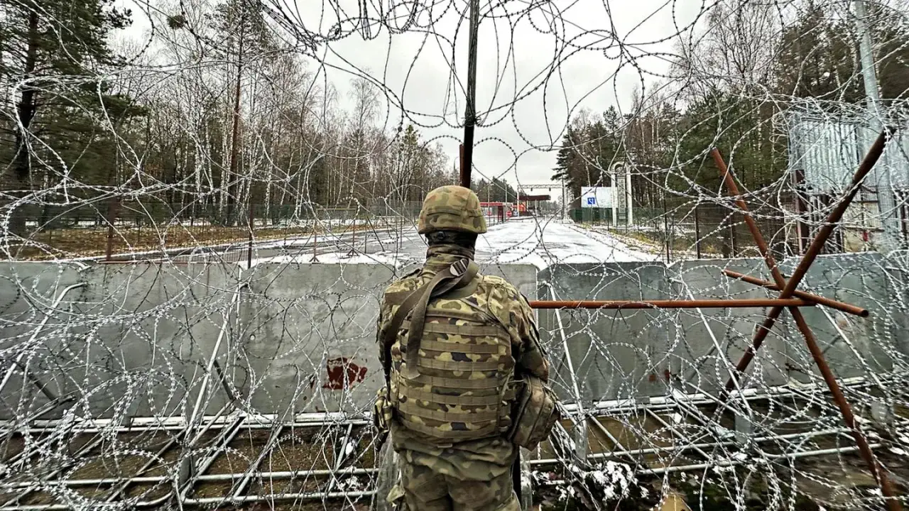 Żołnierz w kamuflażu obserwuje teren za zasiekami z drutu kolczastego. Czy w Białorusi jest bezpiecznie?