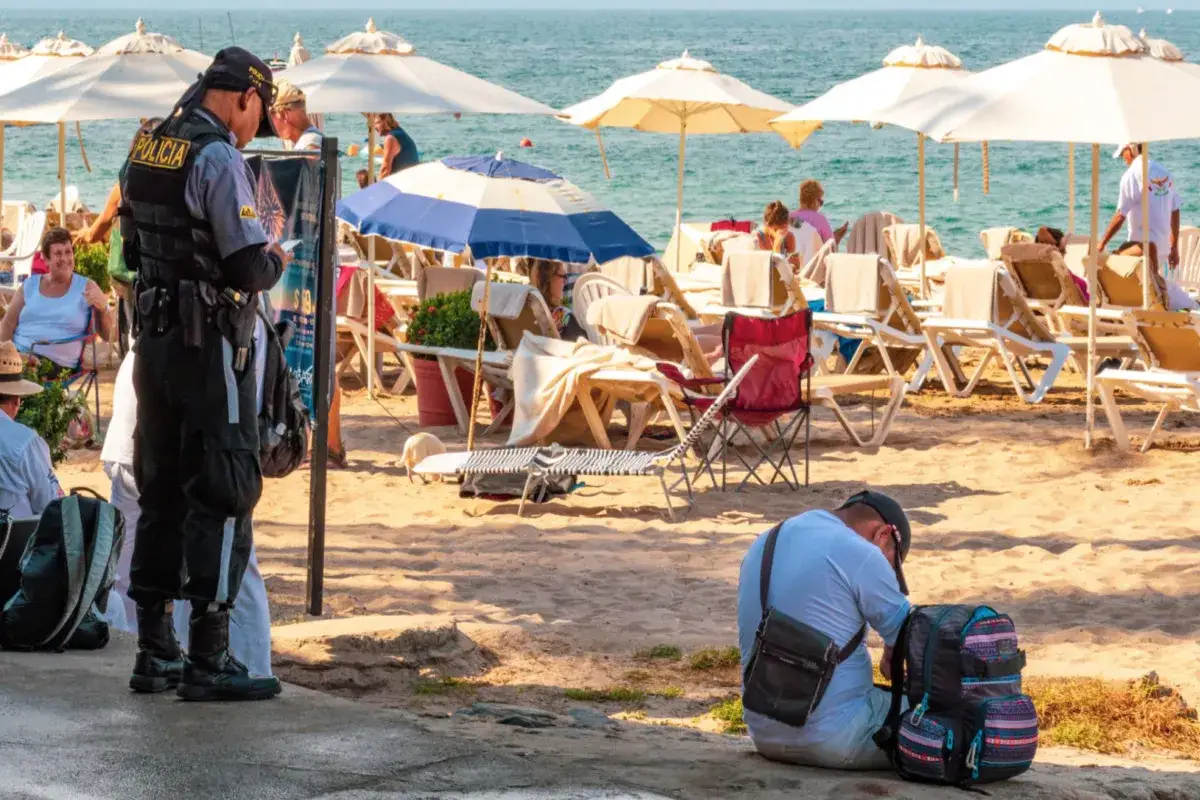 Policjant na plaży w Nicei, wśród turystów i leżaków. Czy Nicea jest niebezpieczna? Obecność policji może budzić pytania.