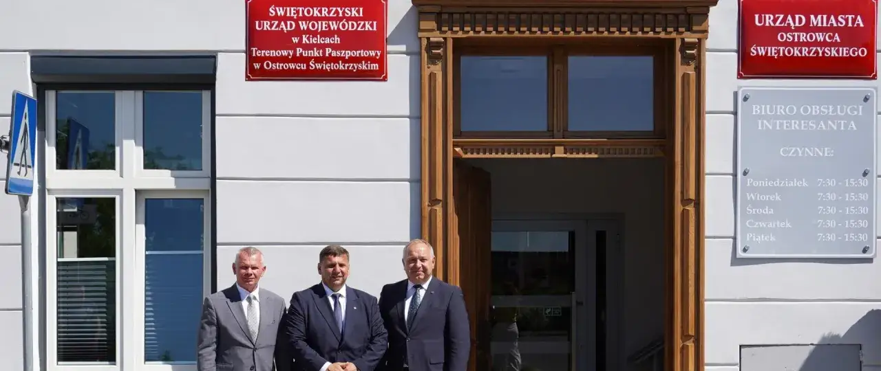 Trzech mężczyzn przed budynkiem Świętokrzyskiego Urzędu Wojewódzkiego w Kielcach, Terenowy Punkt Paszportowy.