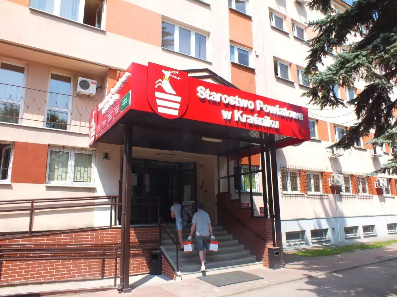 Starostwo Powiatowe w Kraśniku, gdzie można załatwić sprawy paszportowe. Dwie osoby wchodzą do budynku.