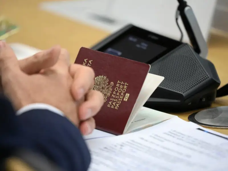 Dłonie złożone na stole, obok paszportu i dokumentów. Szykuje się wyrobienie paszportu w Bydgoszczy.