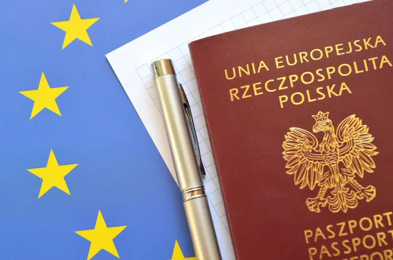 Paszport RP i długopis na tle flagi UE. Planujesz podróż? Sprawdź informacje w biurze paszportowym Łomża.